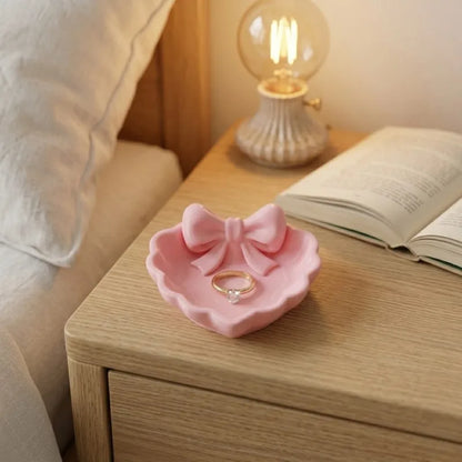 A heart-shaped jewelry tray with a pink bow, made using 3D printing technology, is suitable for placement on a dressing table, s