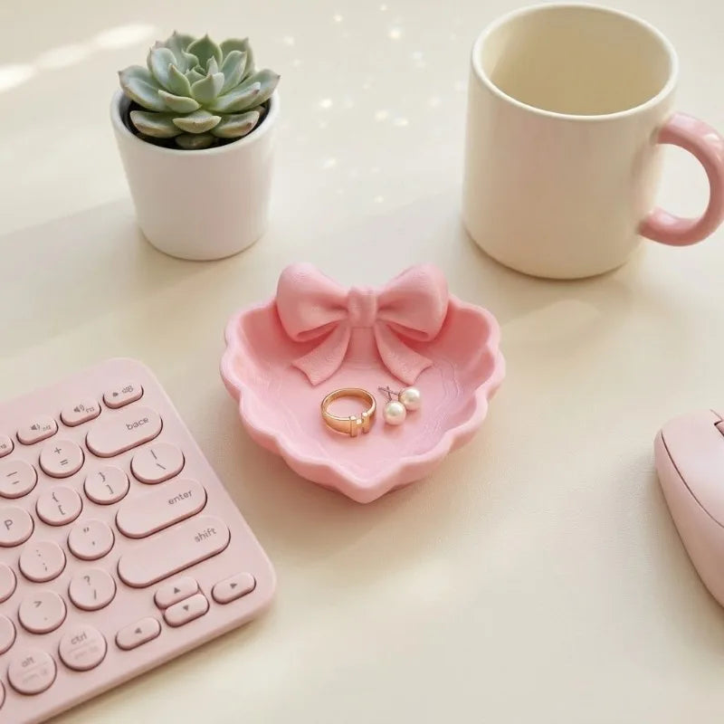 A heart-shaped jewelry tray with a pink bow, made using 3D printing technology, is suitable for placement on a dressing table, s