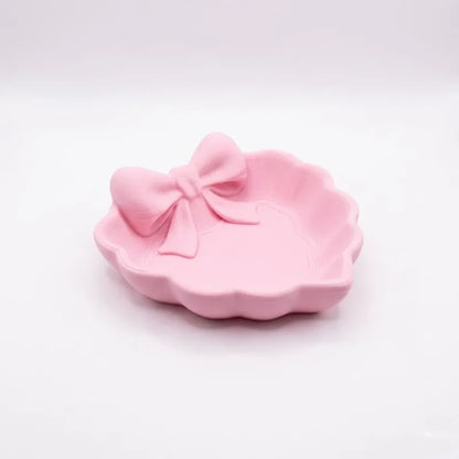 A heart-shaped jewelry tray with a pink bow, made using 3D printing technology, is suitable for placement on a dressing table, s